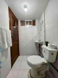 a white bathroom with a toilet and a sink at Hermosa habitación con terraza y vista al pastaza in Baños