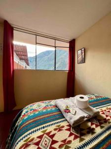 a bedroom with a bed and a window with a roll of toilet paper at Hermosa habitación con terraza y vista al pastaza in Baños
