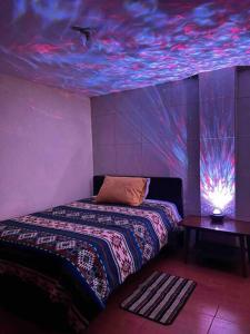 a bedroom with a bed with a purple ceiling at Hermosa habitación con terraza y vista al pastaza in Baños
