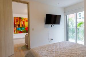 Habitech soho 55-2 في بارانكويلا: غرفة نوم مع سرير وتلفزيون بشاشة مسطحة على الحائط