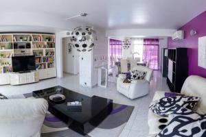 a living room with purple walls and white furniture at La Villa Mussanda avec piscine in Baie-Mahault