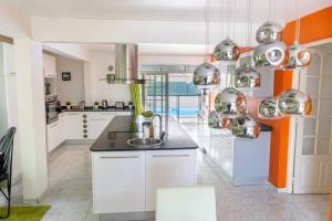 - une cuisine avec des placards blancs et un évier dans l'établissement La Villa Mussanda avec piscine, à Baie-Mahault