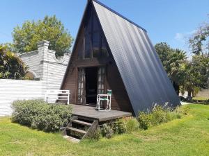 ein winziges Haus mit schwarzem Dach und einer Veranda in der Unterkunft Ala de Colibri in Ramallo