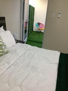 Cama blanca en habitación con alfombra verde en Minutes away from Mangel Halto Beach, en Savaneta