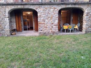 a patio with chairs and a table in a stone building at Chambres d'hôtes du Péras in Saint-Jean-du-Gard