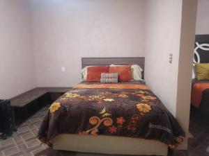 ein Schlafzimmer mit einem Bett mit einer braunen Decke in der Unterkunft La casa de las flores in Zacatlán