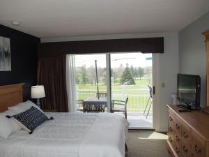 a bedroom with a bed and a television and a balcony at The Grand Getaway - Gorgeous And Great Location! in Traverse City