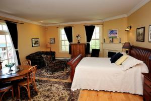 a bedroom with a bed and a table and a fireplace at Barachois Inn in Rustico