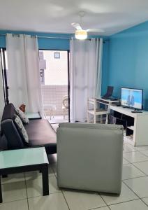 a living room with a couch and a desk with a computer at Apartamento Monte Paradiso in Maceió