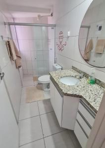 y baño con lavabo, aseo y espejo. en Apartamento Monte Paradiso, en Maceió