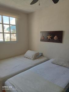two twin beds in a room with a window at Departamento en puente del mar in Acapulco
