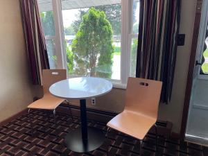 a table and two chairs in a room with a window at FairBridge Inn Express Milford in Milford