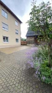 une maison dotée d'une allée en briques avec des fleurs violettes dans l'établissement ST-Apartment Charming 1 mit Terrasse und Garten, 3 Zimmer in Geislingen, à Geislingen an der Steige