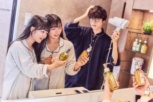 two girls and a boy standing in front of a mirror at Hotel Pasela Living in Tokyo