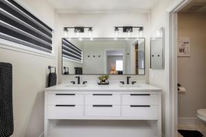 La salle de bains blanche est pourvue d'un lavabo et d'un miroir. dans l'établissement Single Story minutes from Summerlin with RV Parking & Dog Friendly, à Las Vegas