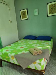 a bedroom with a green bed with towels on it at Langkawi Village Budget Rooms in Pantai Cenang