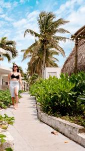 a woman walking down a sidewalk next to a palm tree at Hotel Bungalows Marbella Costa Esmeralda in Monte Gordo