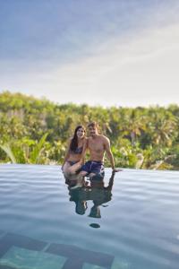 a man and a woman are sitting in the water at Beten Juwet in Nusa Penida