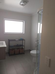 een badkamer met een toilet, een raam en een douche bij Relax and unwind in Magical Matarangi in Matarangi
