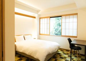 a bedroom with a bed and a desk and windows at 初音(はつね) in Kyoto