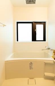 ein Bad mit einer Badewanne und einem Fenster in der Unterkunft 初音(はつね) in Kyoto