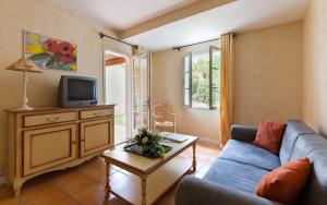 a living room with a blue couch and a tv at Lagrange Vacances Domaine de Fayence in Fayence