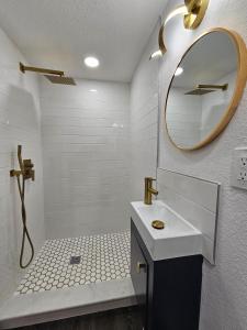 Baño blanco con lavabo y espejo en The Hideaway DT Orlando Tiny Home w Free Parking, en Orlando