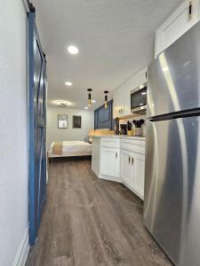 a kitchen with white cabinets and a refrigerator at The Hideaway DT Orlando Tiny Home w Free Parking in Orlando