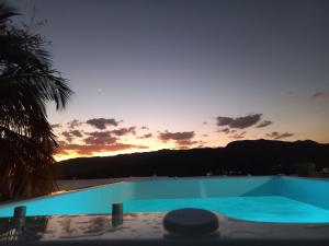 una piscina azul con puesta de sol en el fondo en Cobertura com Incrível Vista de Cinema para o Mar, en Ilhabela