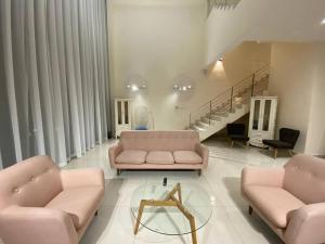 a living room with two pink couches and a glass table at Puchong New Private Pool & Jacuzzi up to 30 Pax in Puchong