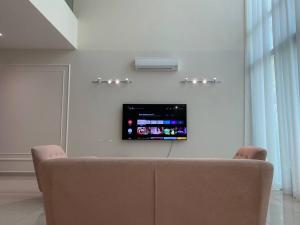 a couch in a living room with a tv on the wall at Puchong New Private Pool & Jacuzzi up to 30 Pax in Puchong