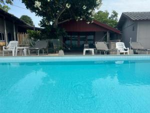 a large blue swimming pool with chairs and a house at The Cosy Koh Phangan in Thongsala