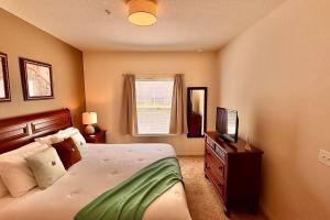 Dormitorio con cama y tocador con TV en ABC Vacation Homes, en Kissimmee