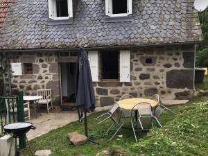 a table and chairs in front of a stone house at Gîte Saint-Projet-de-Salers, 3 pièces, 4 personnes - FR-1-742-132 in Saint-Projet-de-Salers