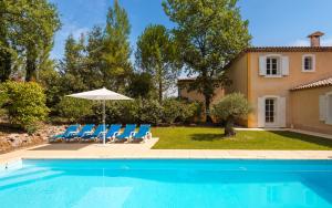 a pool with chairs and an umbrella and a house at Lagrange Vacances Domaine de Fayence in Fayence