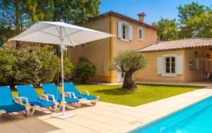a group of chairs and an umbrella next to a pool at Lagrange Vacances Domaine de Fayence in Fayence