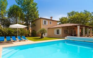 a pool in front of a house with chairs and an umbrella at Lagrange Vacances Domaine de Fayence in Fayence