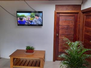 a television hanging on a wall with a room with a table at Casa Verde Descanso in Baños