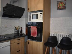 a kitchen with a microwave and two stools in it at Bel appartement T3 - centre-ville de Font-Romeu - FR-1-580-95 in Font Romeu Odeillo Via +5 photos