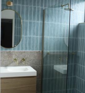 een blauw betegelde badkamer met een wastafel en een spiegel bij Lorne Surf Apartments in Lorne
