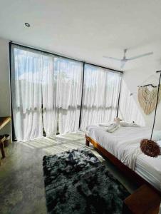 1 dormitorio con 1 cama grande y ventanas grandes en Lush Tulum Rooftop Condo with Ensuite Pool & Wifi, en Tulum