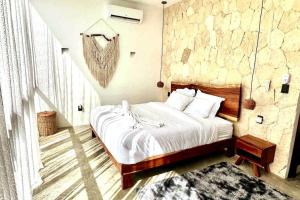 1 dormitorio con cama y pared de piedra en Lush Tulum Rooftop Condo with Ensuite Pool & Wifi, en Tulum