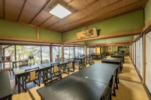 un comedor con mesas, sillas y ventanas en Temple Lodging Shukubo Kakurinbo en Minobu