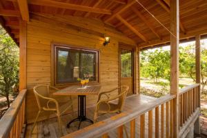 un porche de una cabaña de madera con mesa y sillas en Secret Garden Hotel & Bungalows, en Cıralı