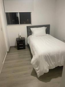 1 dormitorio con cama blanca y mesita de noche en Apartamento con vista al lago., en Paipa