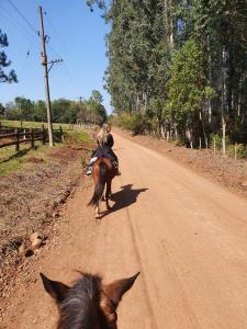 Un paio di persone che cavalcano un cavallo lungo una strada sterrata. di Estancia La Paulina!!! 1 hora de las Cataratas!!! a Eldorado