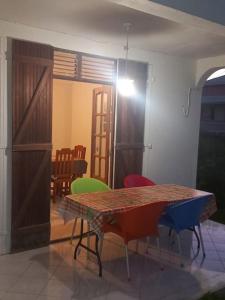 ein Esszimmer mit einem Tisch und bunten Stühlen in der Unterkunft Charmant logement à 6min en voiture de la plage. in Anse-Bertrand
