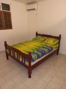 - un lit avec un cadre en bois et une couverture jaune dans l'établissement Charmant logement à 6min en voiture de la plage., à Anse-Bertrand