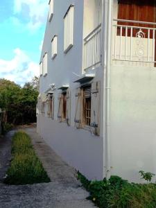 - un bâtiment blanc avec des fenêtres sur le côté dans l'établissement Charmant logement à 6min en voiture de la plage., à Anse-Bertrand