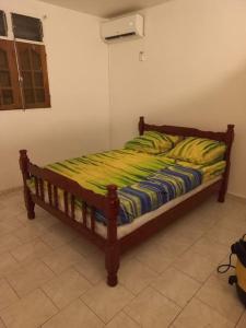 - un lit avec une couette jaune et bleue dans l'établissement Charmant logement à 6min en voiture de la plage., à Anse-Bertrand